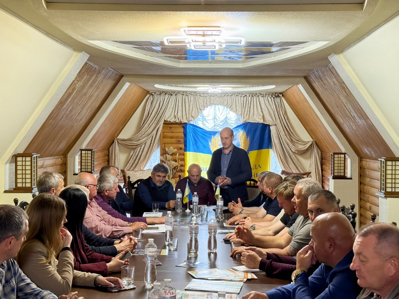 Учасники засідання сидить за столом у залі, директор Департаменту Олег Сідоров стоїть