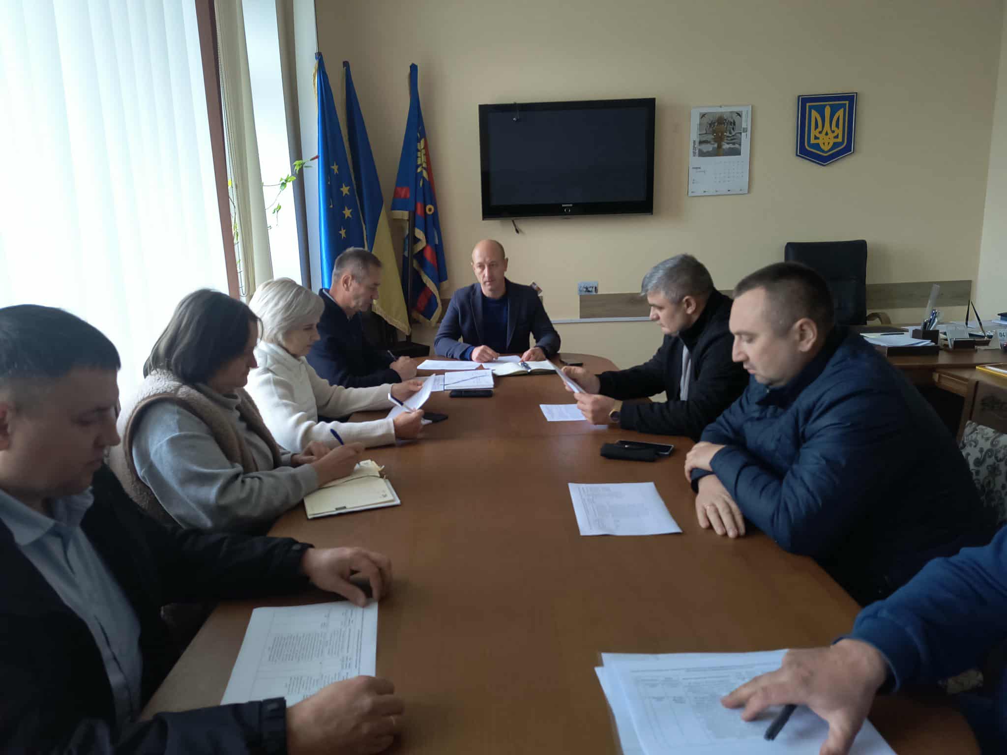 В кабінеті за робочим  столом сидят працівники, перед ними документи та записники