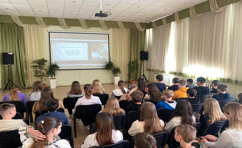 Люди сидять у залі. На великому екрані транслюються слайди презентації.