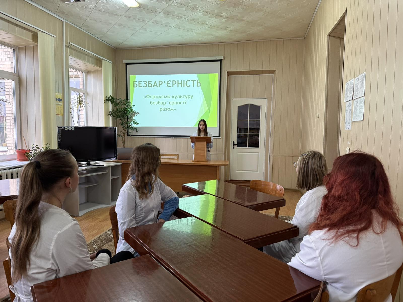 Фото з заходів. Люди в аудиторії сидять за столами