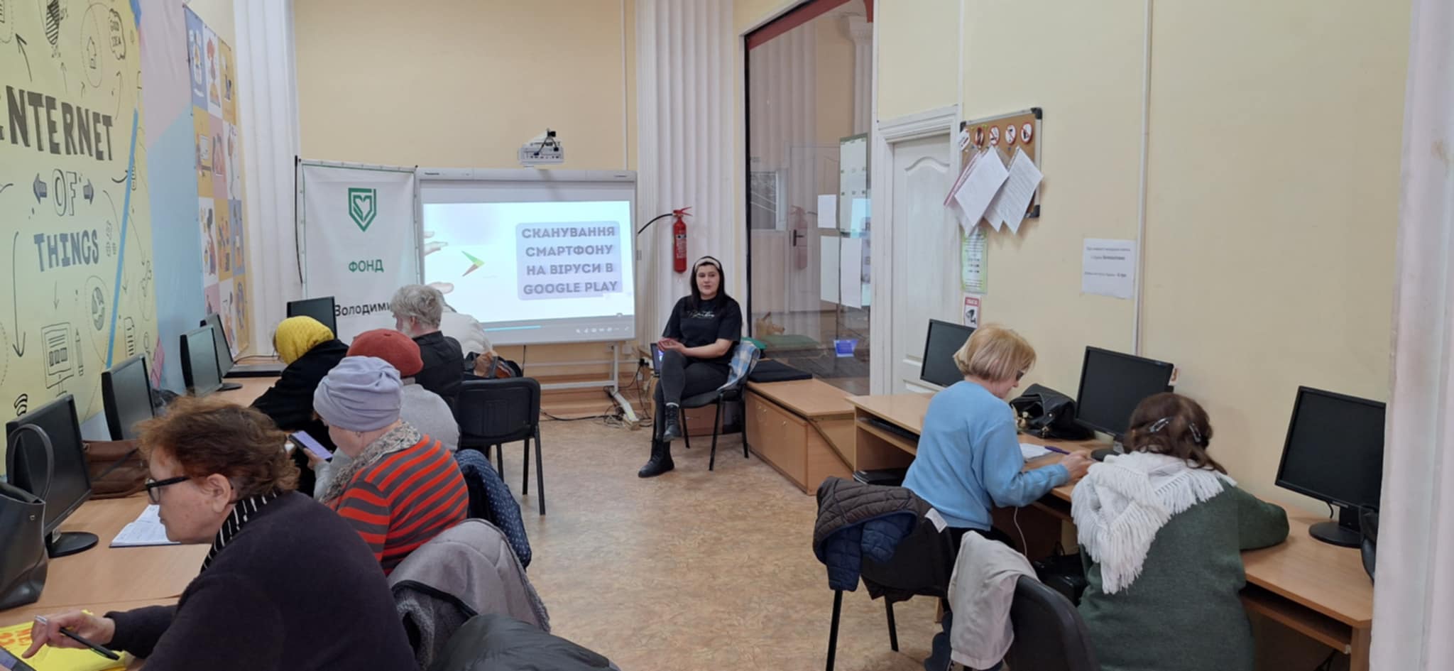 Навчальне заняття в комп'ютерній аудиторії: учасники сидять за столами, обладнаними комп'ютерами, та уважно слухають викладача