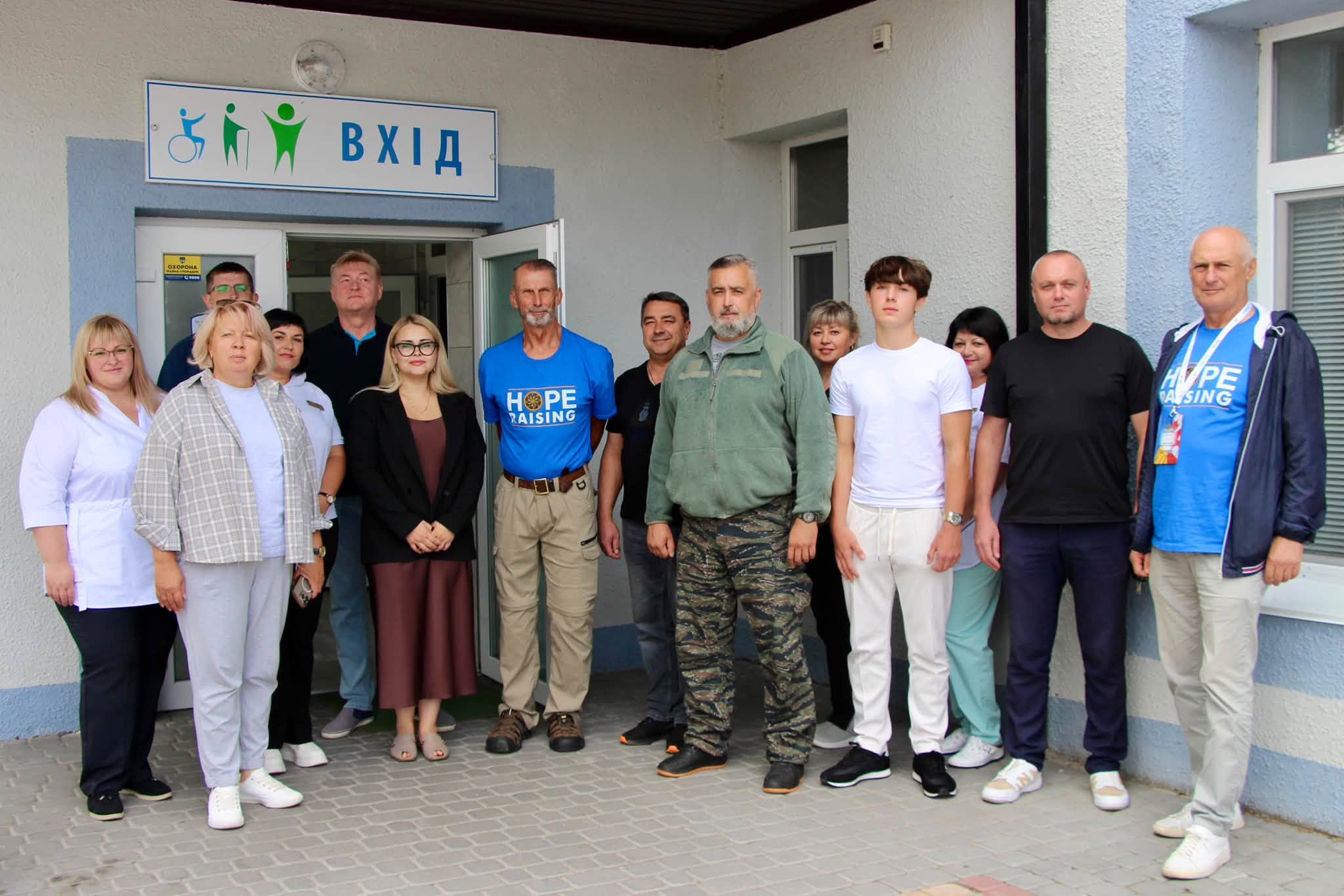 Група людей фотографується біля входу до медичного закладу