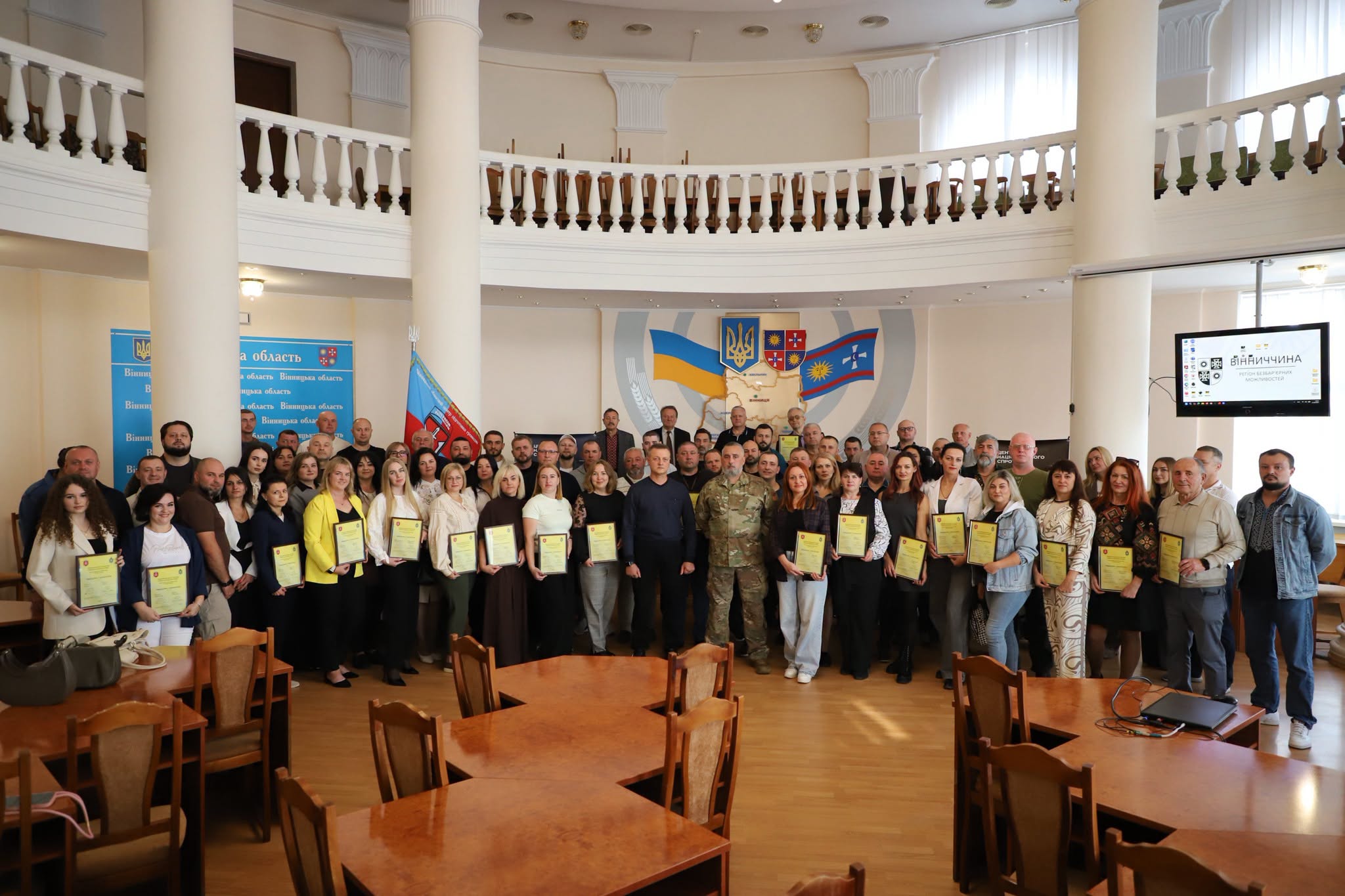 Група людей, що закінчила курс підготовки до національного спротиву, зібрались в приміщенні для спільного фото. 
