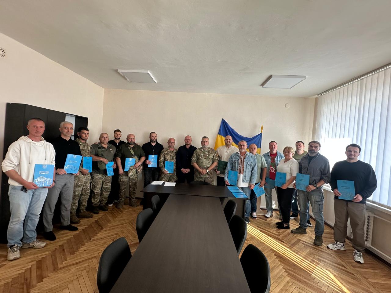 Група людей з грамотами в руках зібрались в приміщенні для спільного фото