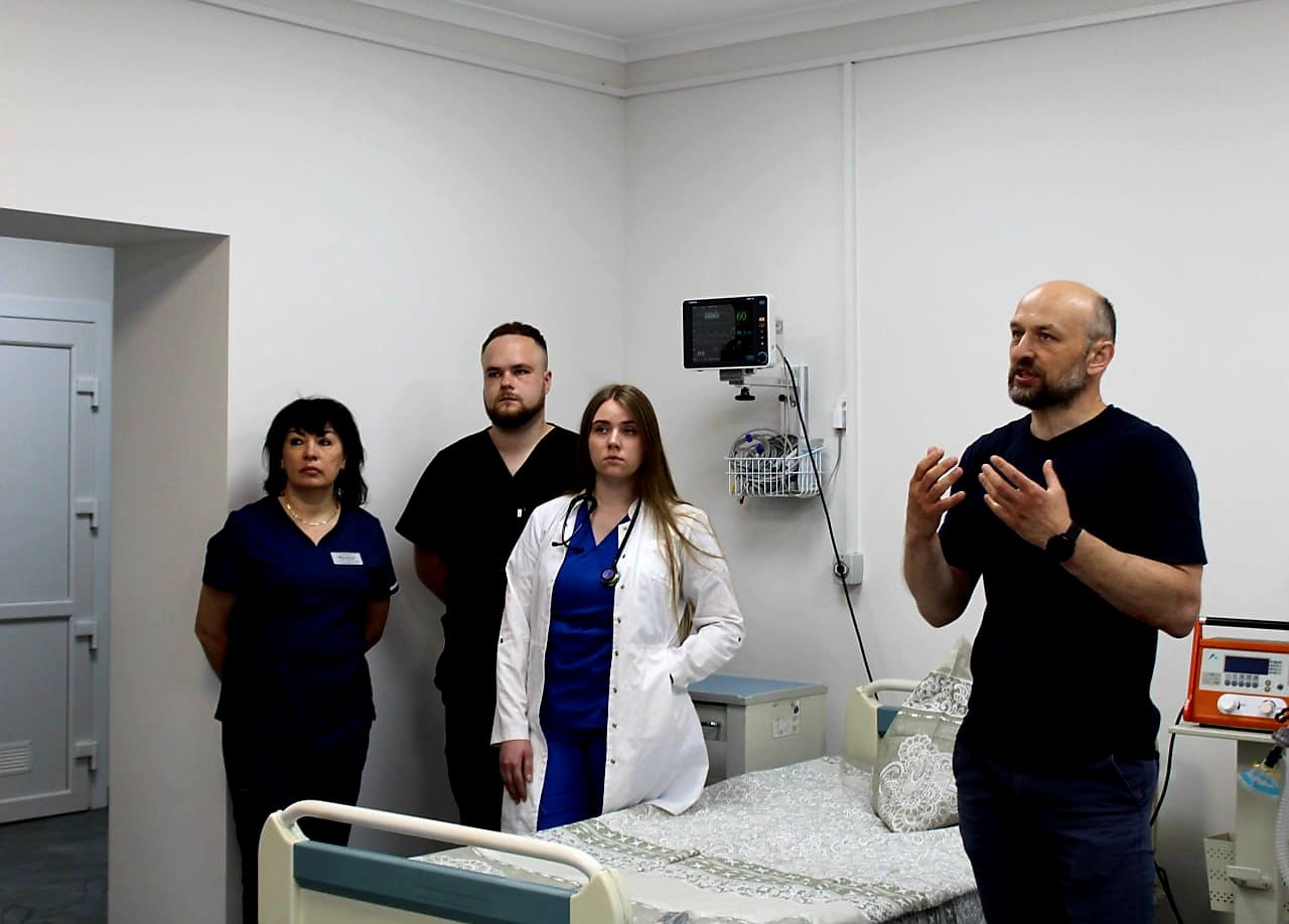 Група людей стоїть перед ліжком у лікарні.