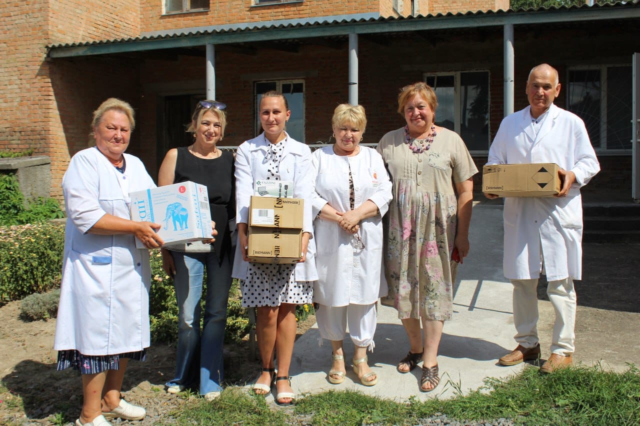 Група людей у білих халатах тримає коробки.