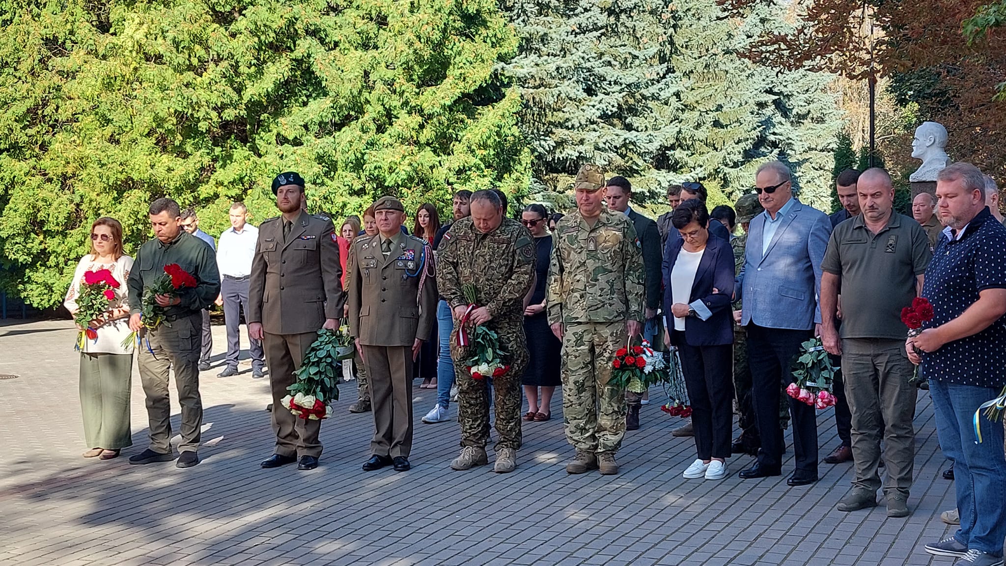 Група людей оточує чоловіка, який тримає квіти.