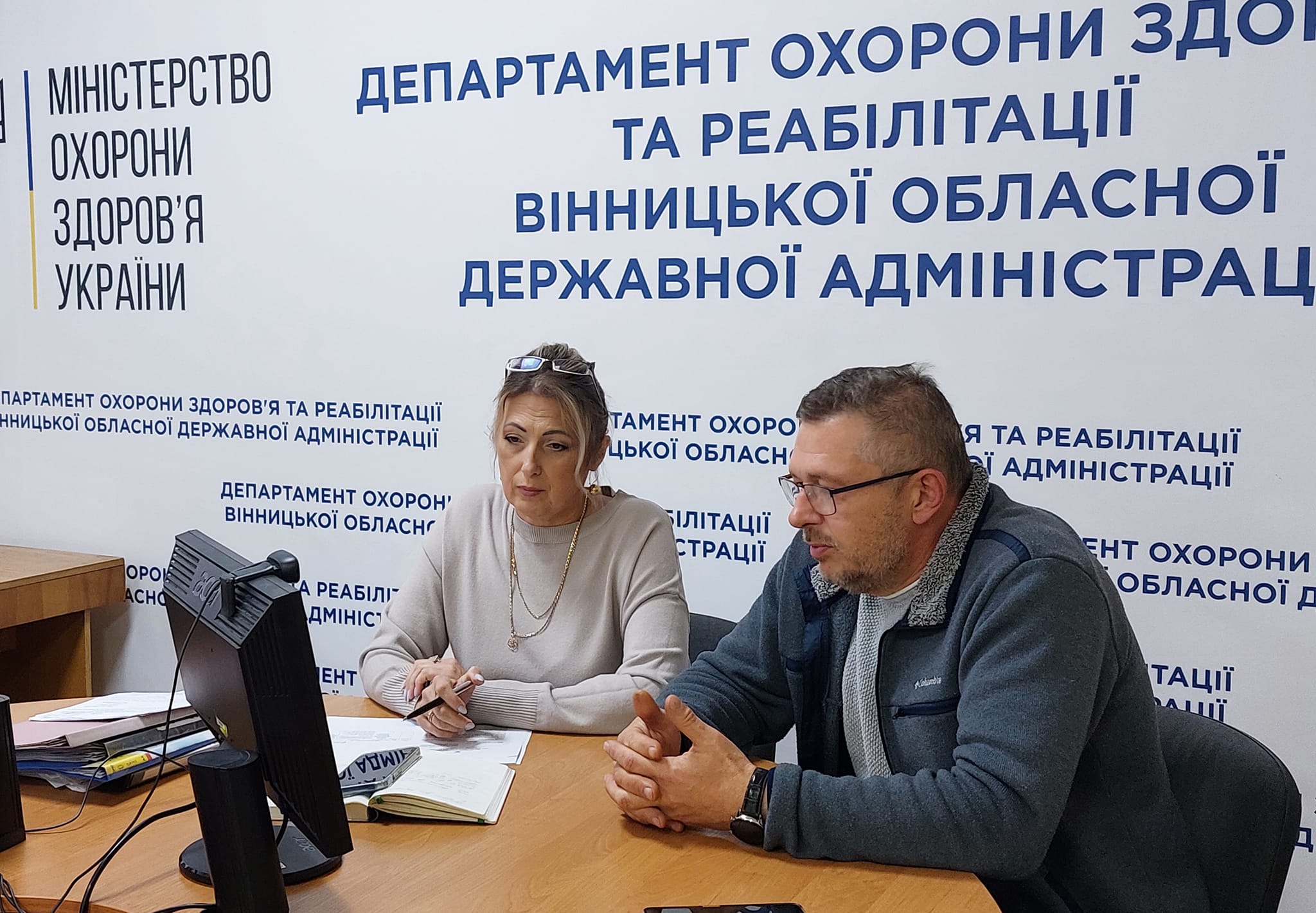 Чоловік і жінка сидять за столом перед комп'ютером, обговорюючи робочі питання.