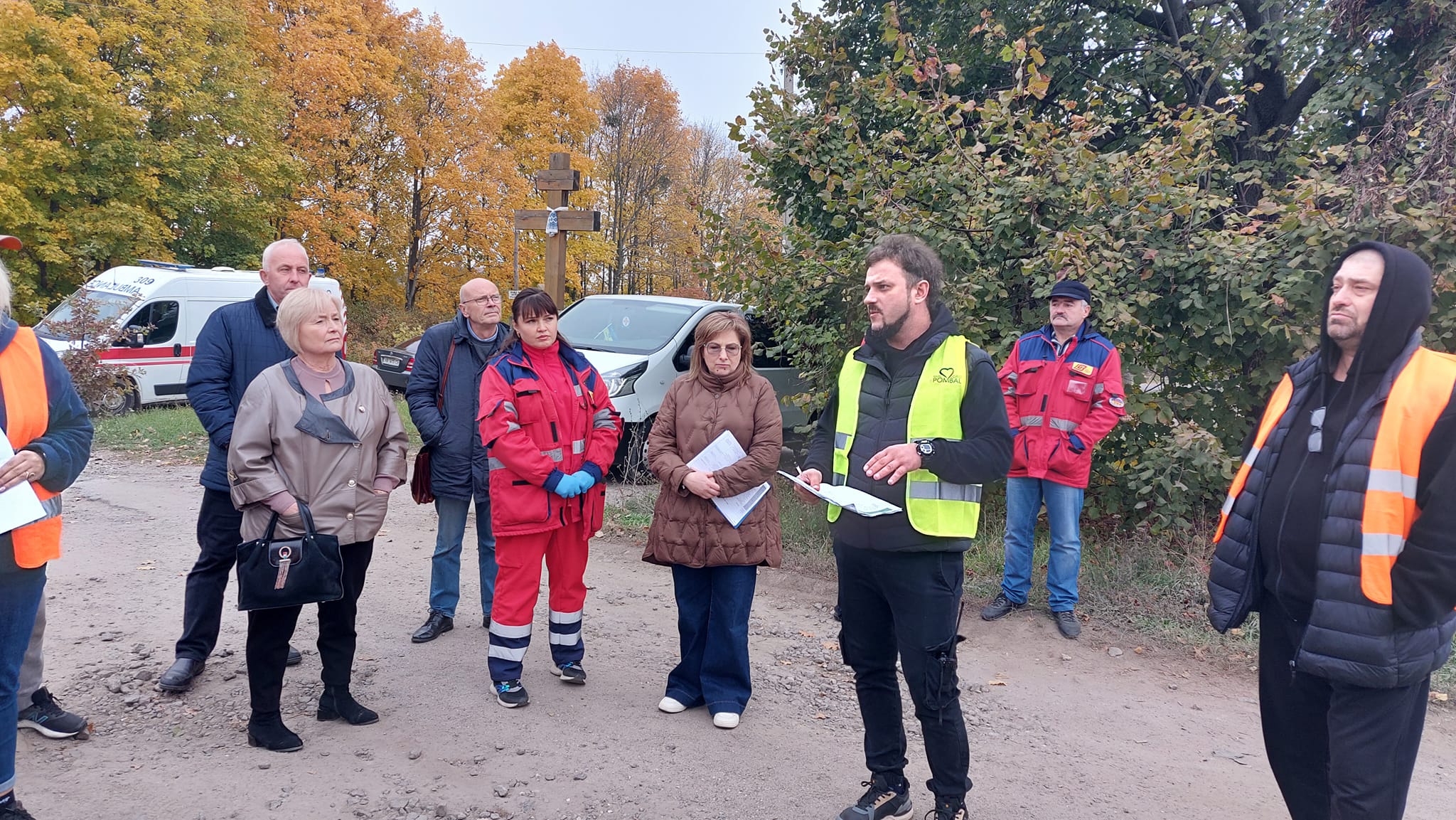 Група людей стоїть на вулиці, серед них чоловік у жилеті, що привертає увагу.