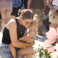 Жінка з дитиною вшановує пам’ять загиблих внаслідок ракетного обстрілу 14 липня 2022 року 
