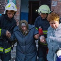 рятувальники допомагають жінкам вийти з будинку