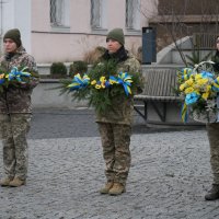 Троє військовослужбовиць з квітковими композиціями в руках