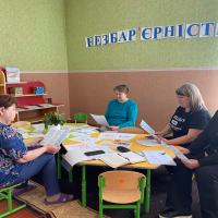 Учасники заходу сидять за круглим столом в аудиторії