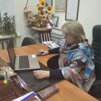 Жінка сидить за столом перед екраном ноутбуку 