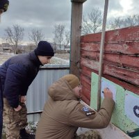 Чоловік робить позначки на мішені та два хлопці, що спостерігають за процесом