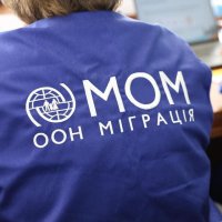 логотип та напис Міжнародної організації з міграції (МОМ) на одязі представника