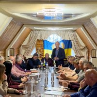 Учасники засідання сидить за столом у залі, директор Департаменту Олег Сідоров стоїть