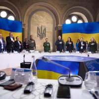Президент Володимир Зеленський та учасники засідання стоять на фоні Прапора України
