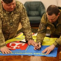 Військові підписують прапор бригади